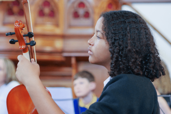 Person holding a musical instrument and looking ahead, image taken from the side