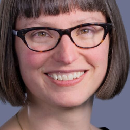 Portrait photo of Katie Lucas, with short hair and glasses