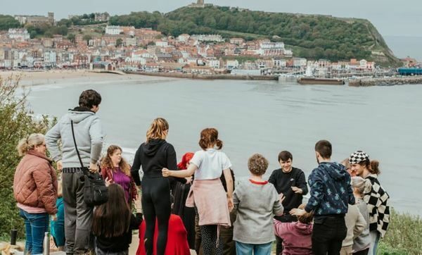 Group of people stood overlooking a bay with water and houses in the distance