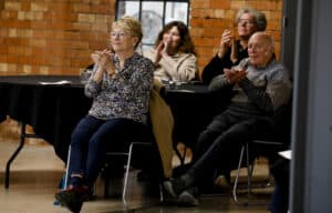 Four audience members show their appreciation for the music in a concert by clapping.