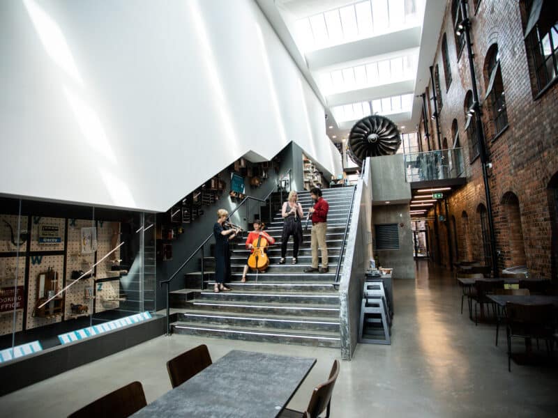 Group of people holding their instruments stood on the steps of a museum