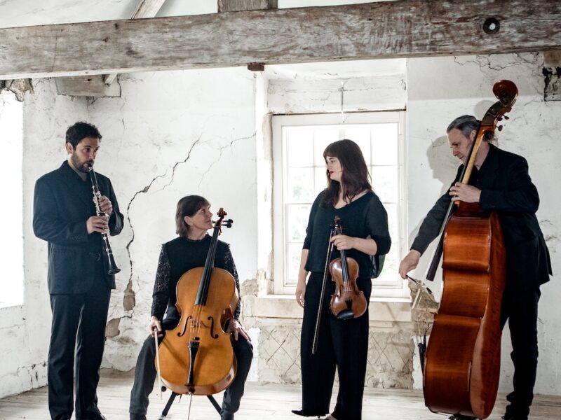 Quartet participants holding their instruments in a rustic looking room