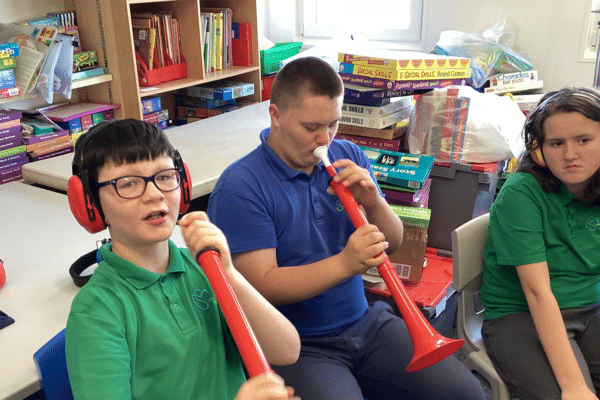 Group of children and young people holding plastic instruments for the Together Through Music project