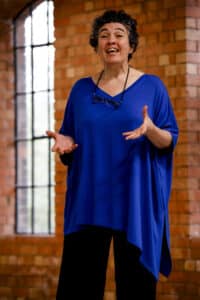 A woman in a blue shawl talks to an audience