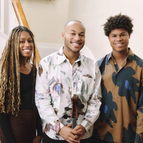 Isata, Sheku and Braimah Kanneh-Mason photographed in front of a staircase and bookshelf